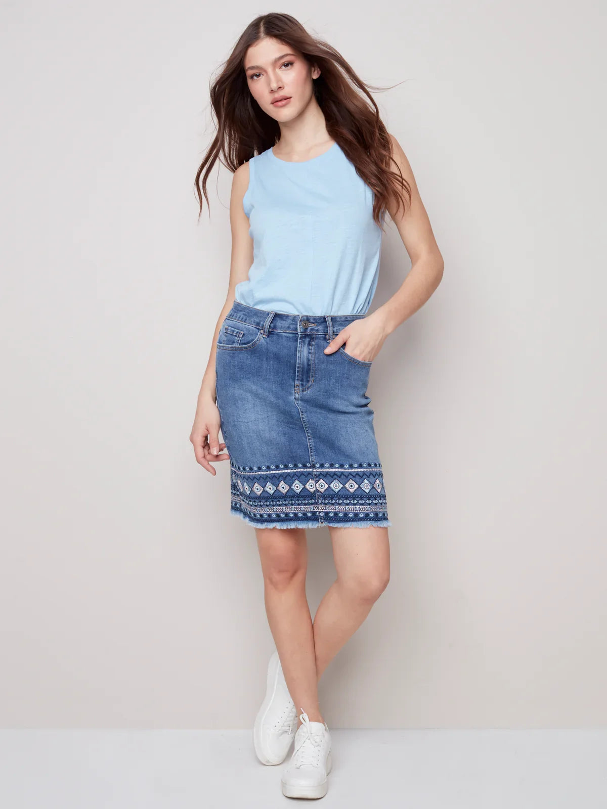 Elegant denim embroidered-cuff skirt styled with a blue tank top, ideal for coastal boutique clothing and summer outings.