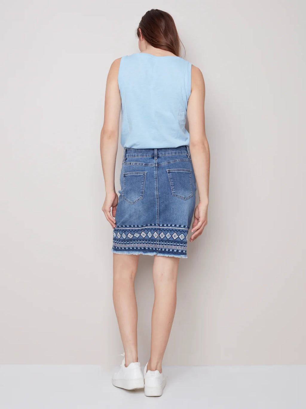 Back view of denim embroidered-cuff skirt paired with a light blue top, perfect for coastal boutique clothing.