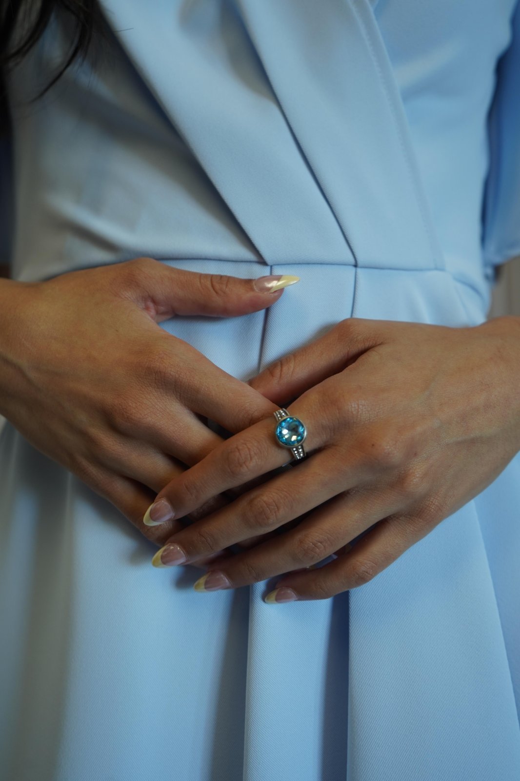 Model wearing a light blue mini wrap dress with feminine ruffles, showcasing a stylish ring. Perfect for beach dresses.