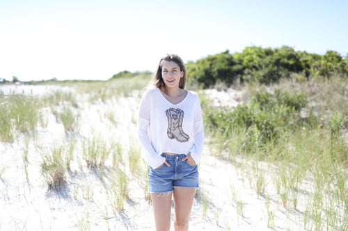 Woman wearing WS Wooden Ships boots sweater-breaker white at beach, showcasing coastal boutique clothing style.