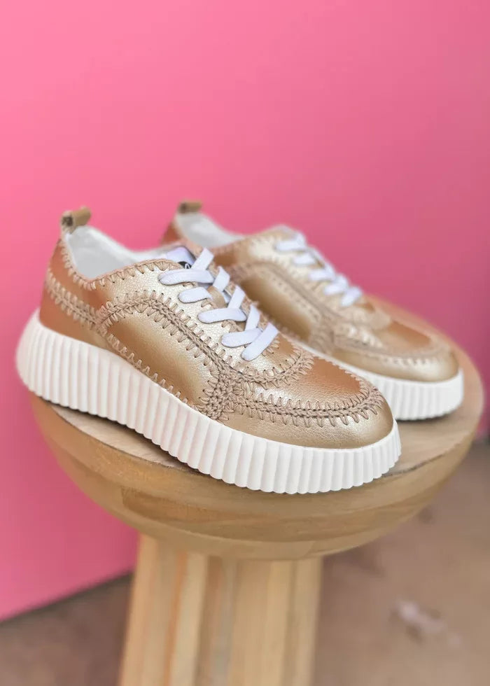 Nelson Gold Sneaker Shoe displayed on a stand, perfect for trendy coastal style at Raggdoll Boutique.