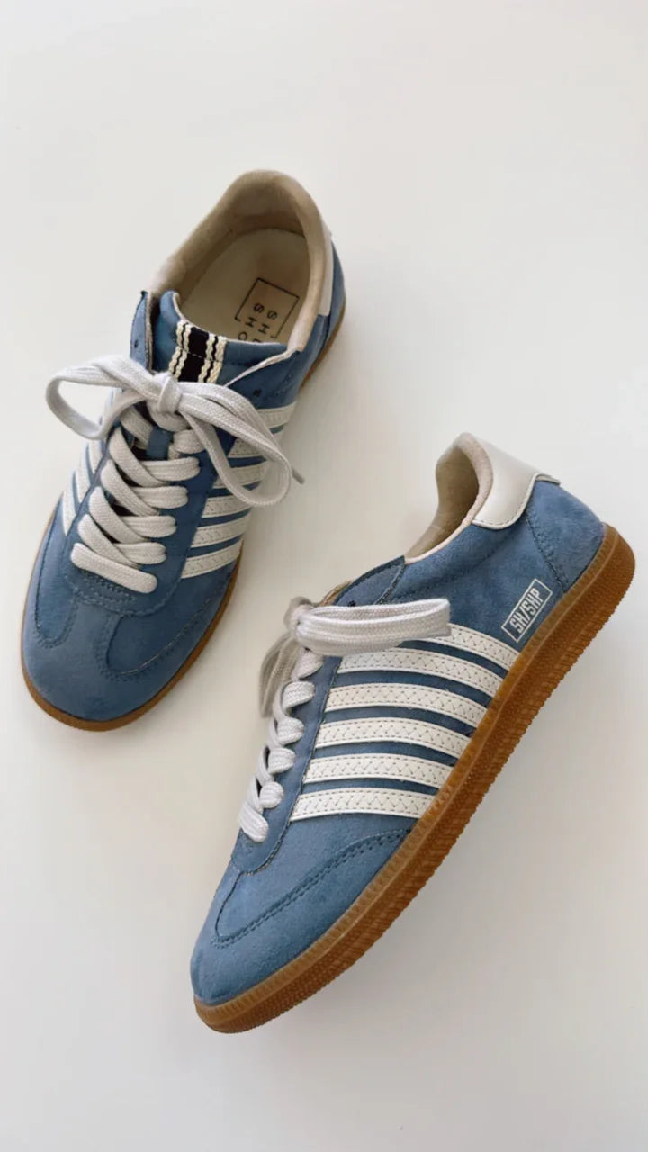 Stylish blue suede tennis shoes with white-beige stripes, perfect for beach dresses and curated women's fashion.