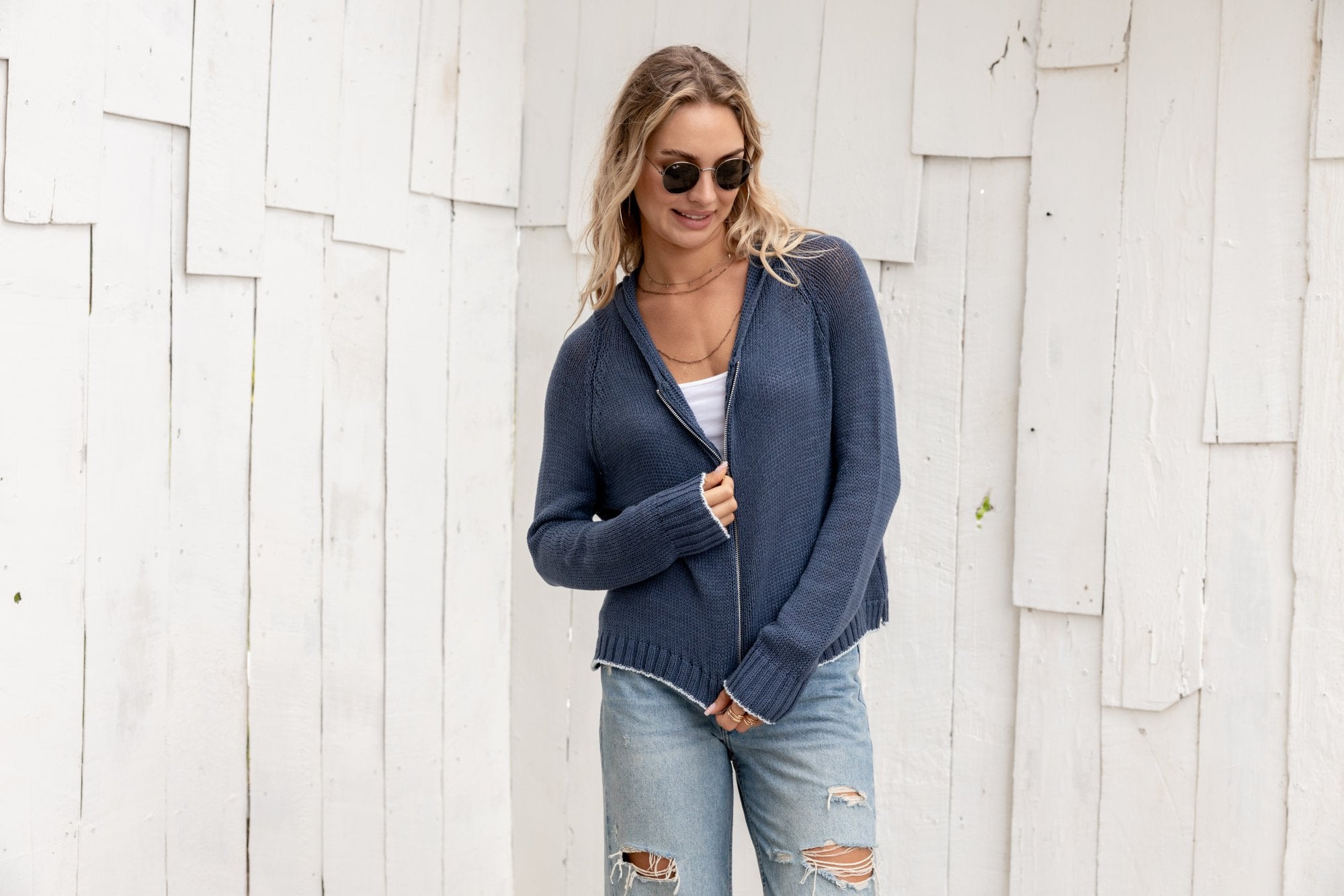 Stylish woman wearing a navy zip hoodie with jeans, perfect for coastal boutique clothing and modern fashion.