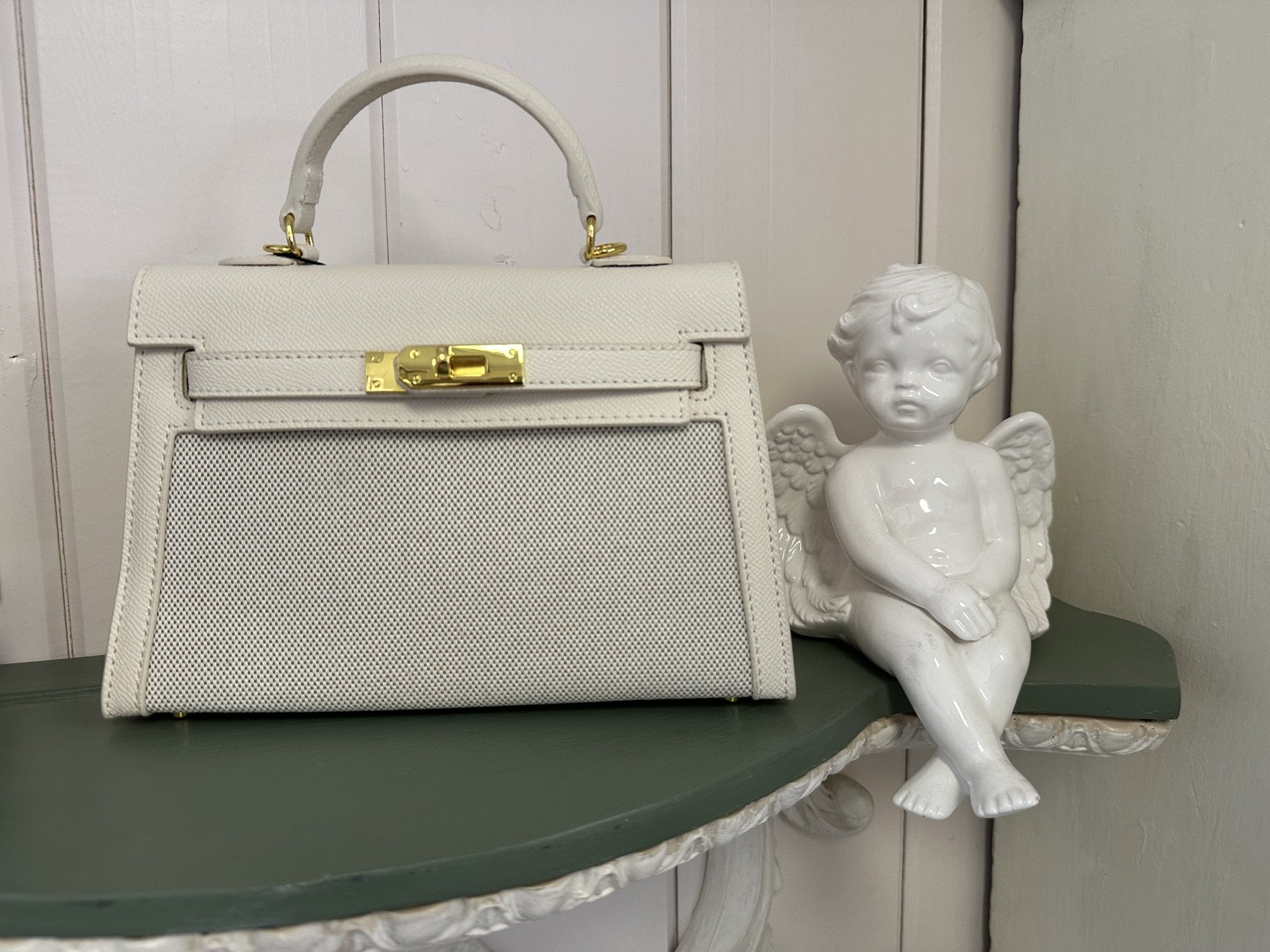 Stylish Nancy Bag displayed on a shelf with a decorative angel statue, ideal for a coastal boutique clothing vibe.