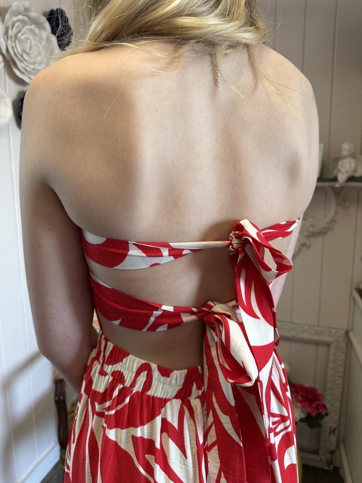 Back view of a red and ivory halter jumpsuit, highlighting its adjustable tie and stylish design for summer outings.
