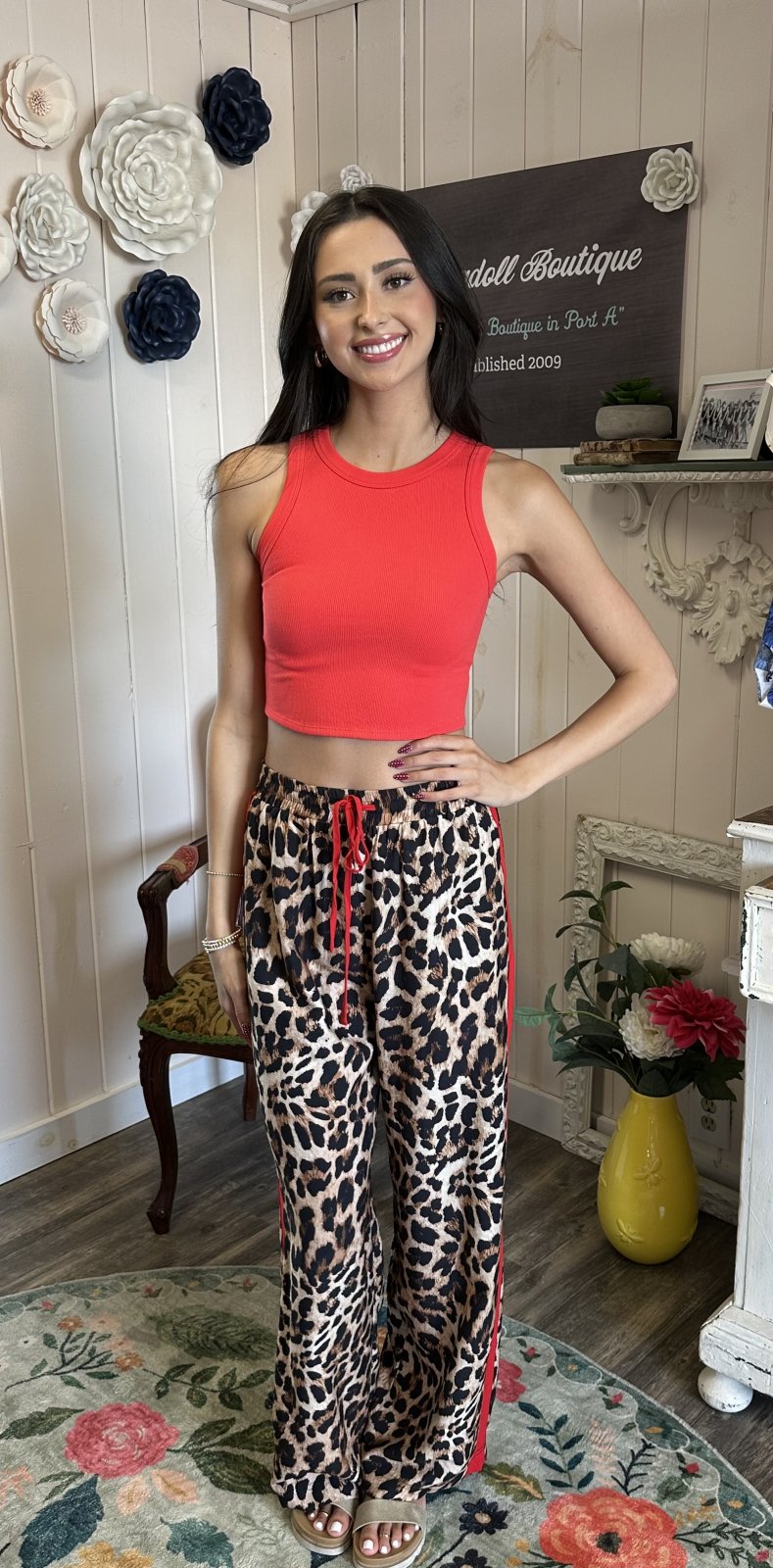 Model showcasing leopard printed track pants with red crop top, a chic addition to coastal boutique clothing.