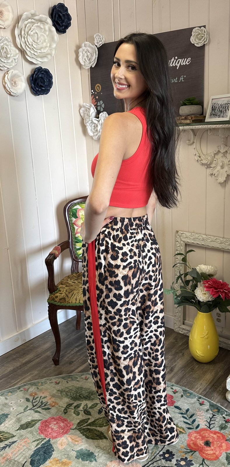 Model showcasing leopard printed track pants with red stripes, embodying stylish comfort from a Port Aransas boutique.