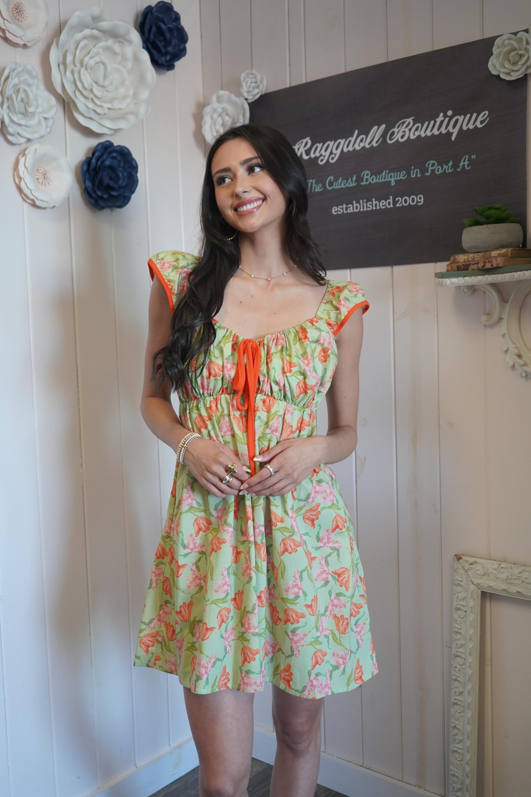 Model wearing a vibrant green and orange floral dress from Raggdoll Boutique, perfect for spring and beach outings.