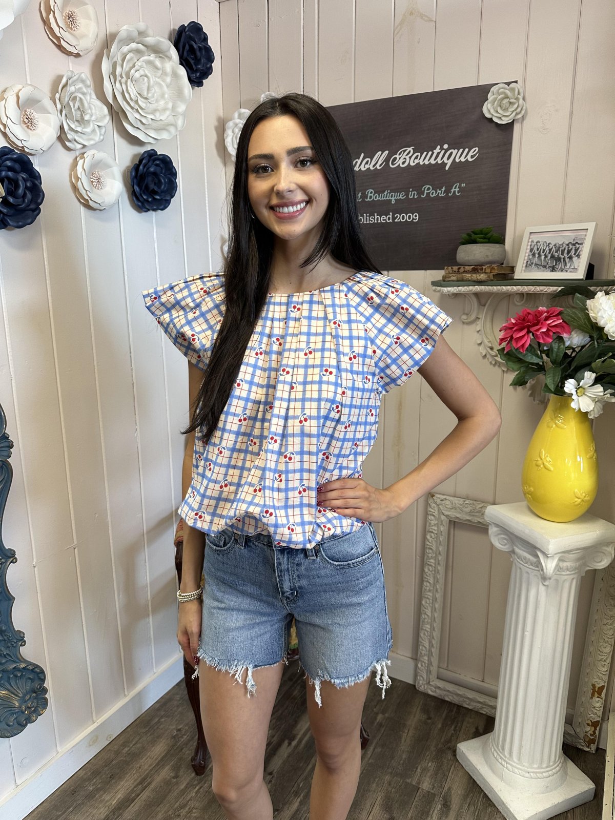 Stylish cherry print blouse paired with denim shorts, perfect for coastal boutique clothing and tropical vacations.