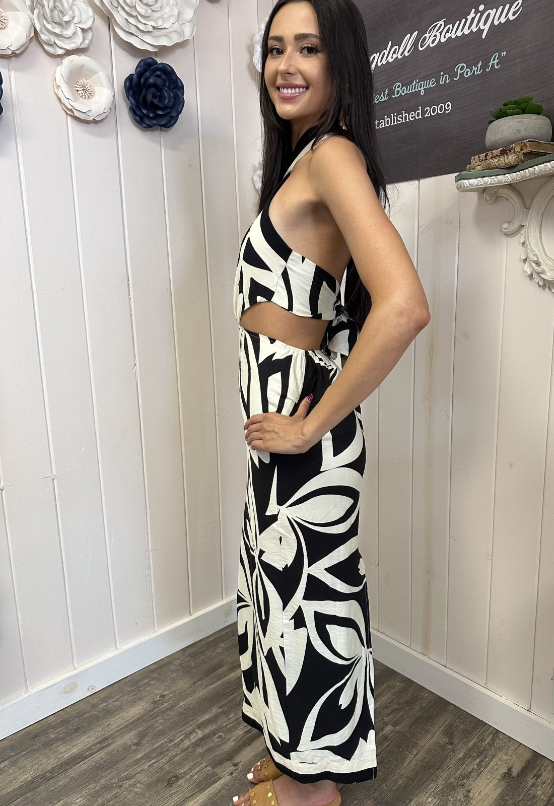 Model wearing a black and white tropical print criss-cross halter midi dress from a Port Aransas boutique, showcasing coastal style.