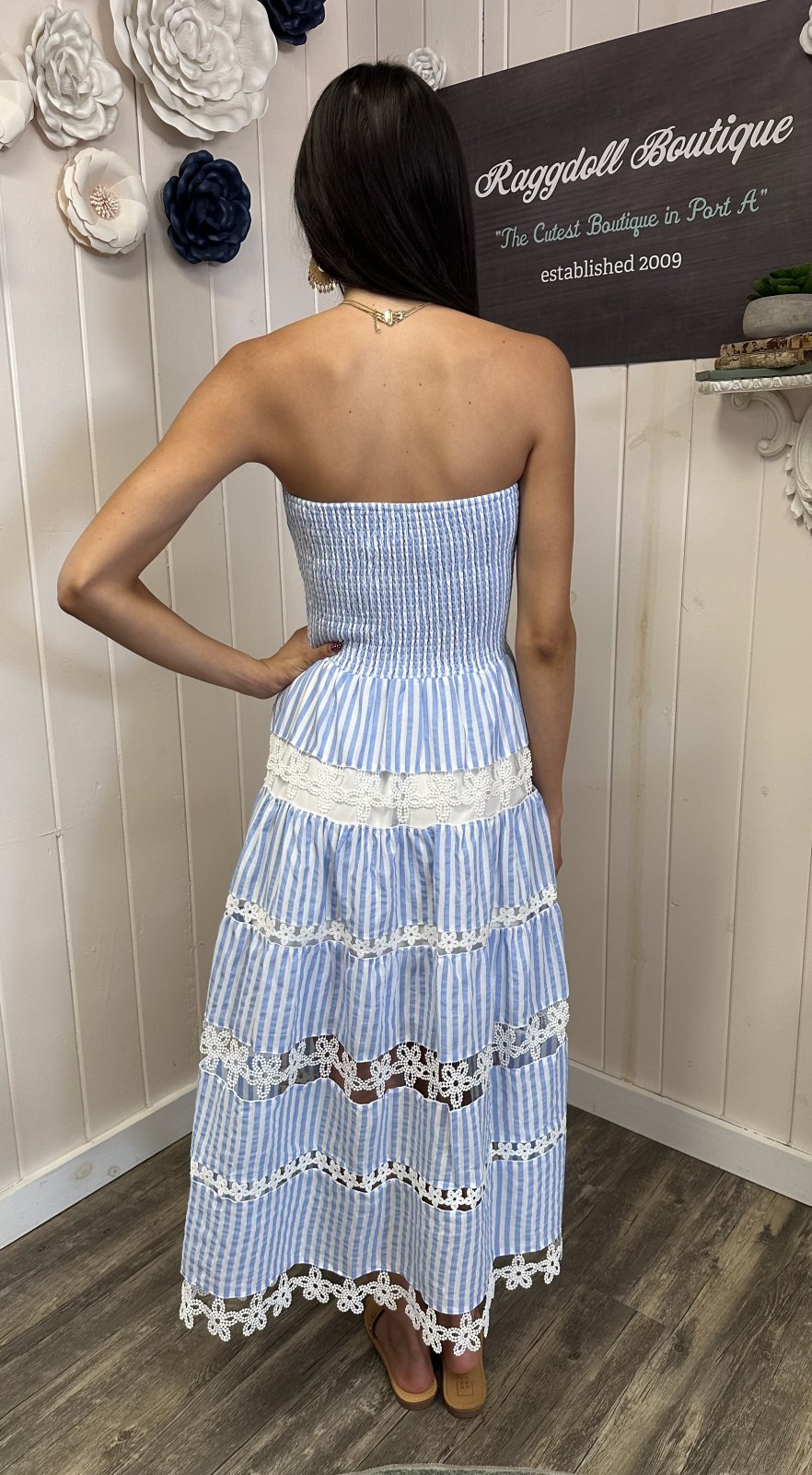 Stylish woman in light blue Alora Dress, featuring smocked bodice and floral lace, perfect for coastal boutique clothing.