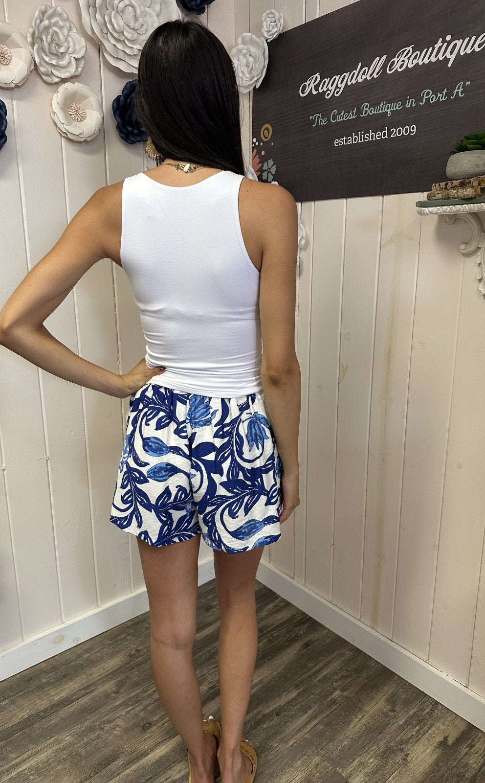 Back view of woman wearing Mia Shorts with blue floral print, ideal for coastal boutique clothing and casual outings.