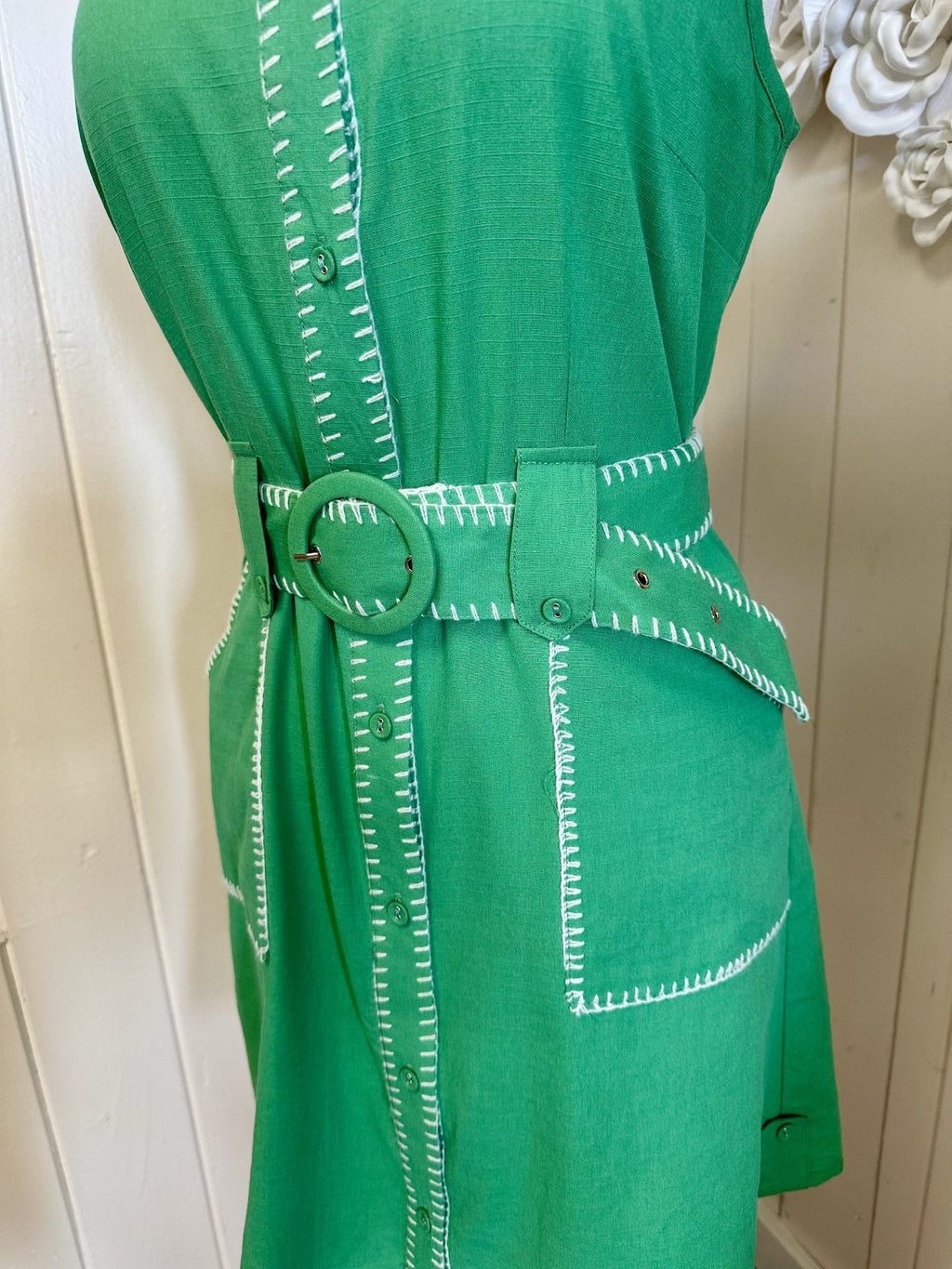 Green sleeveless Daisy Dress with button-down front, white contrast stitching, and matching waist belt from coastal boutique clothing.