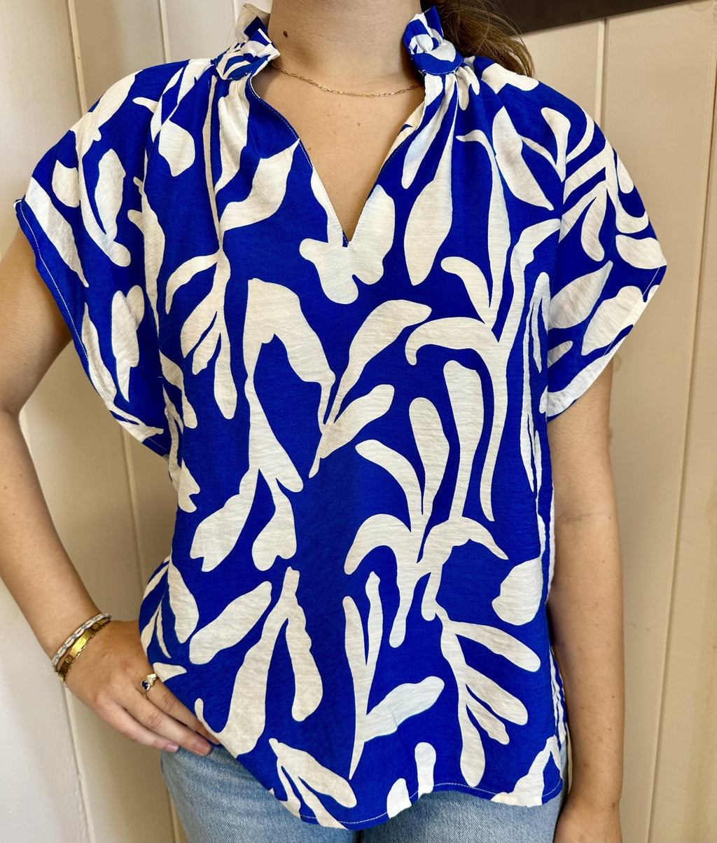 Stylish blue and white ruffle collar top, perfect for coastal boutique fashion and tropical vacations.
