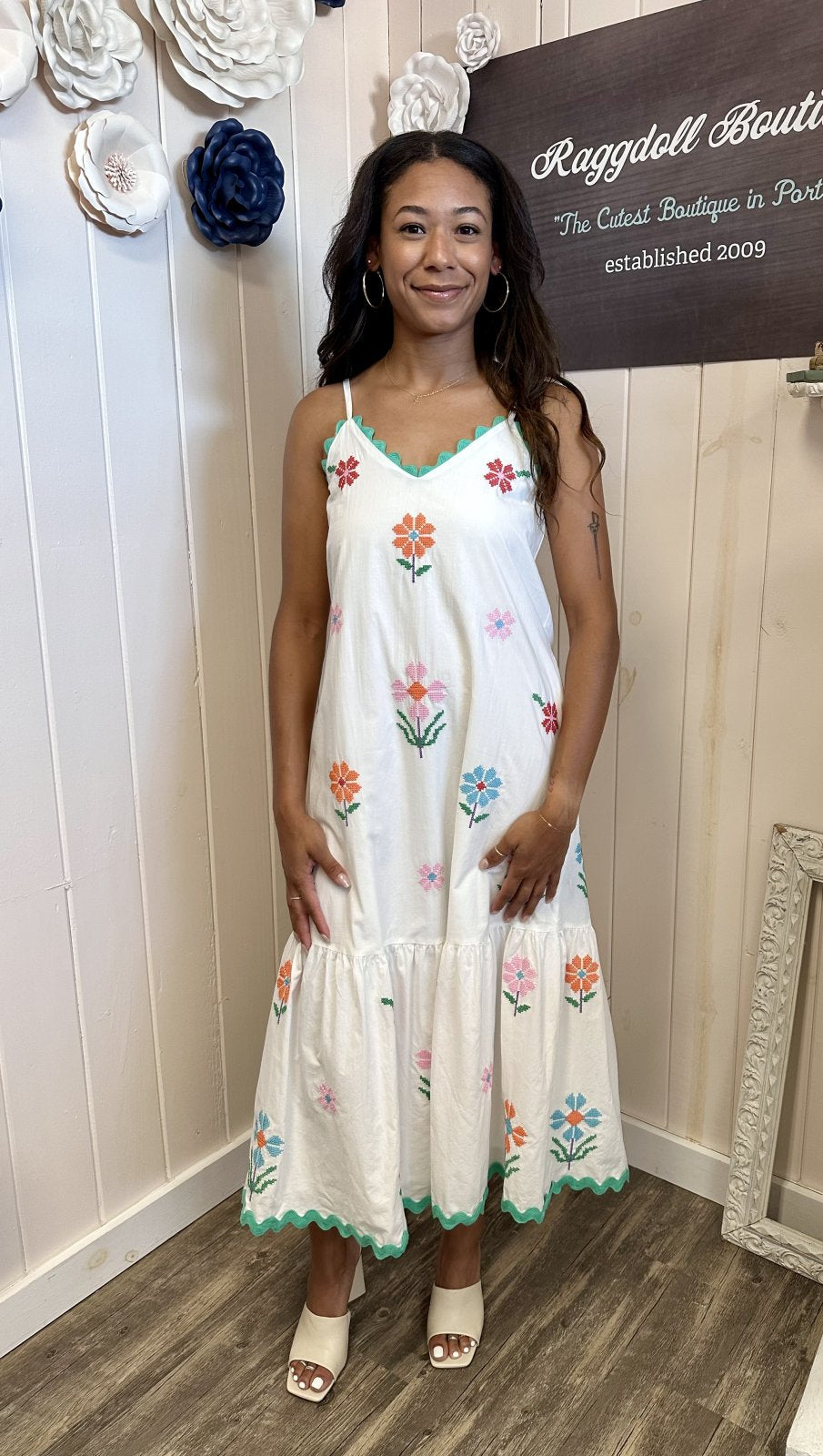 Model wearing the Teagan Dress, a charming midi dress with embroidered flowers, perfect for coastal boutique clothing.