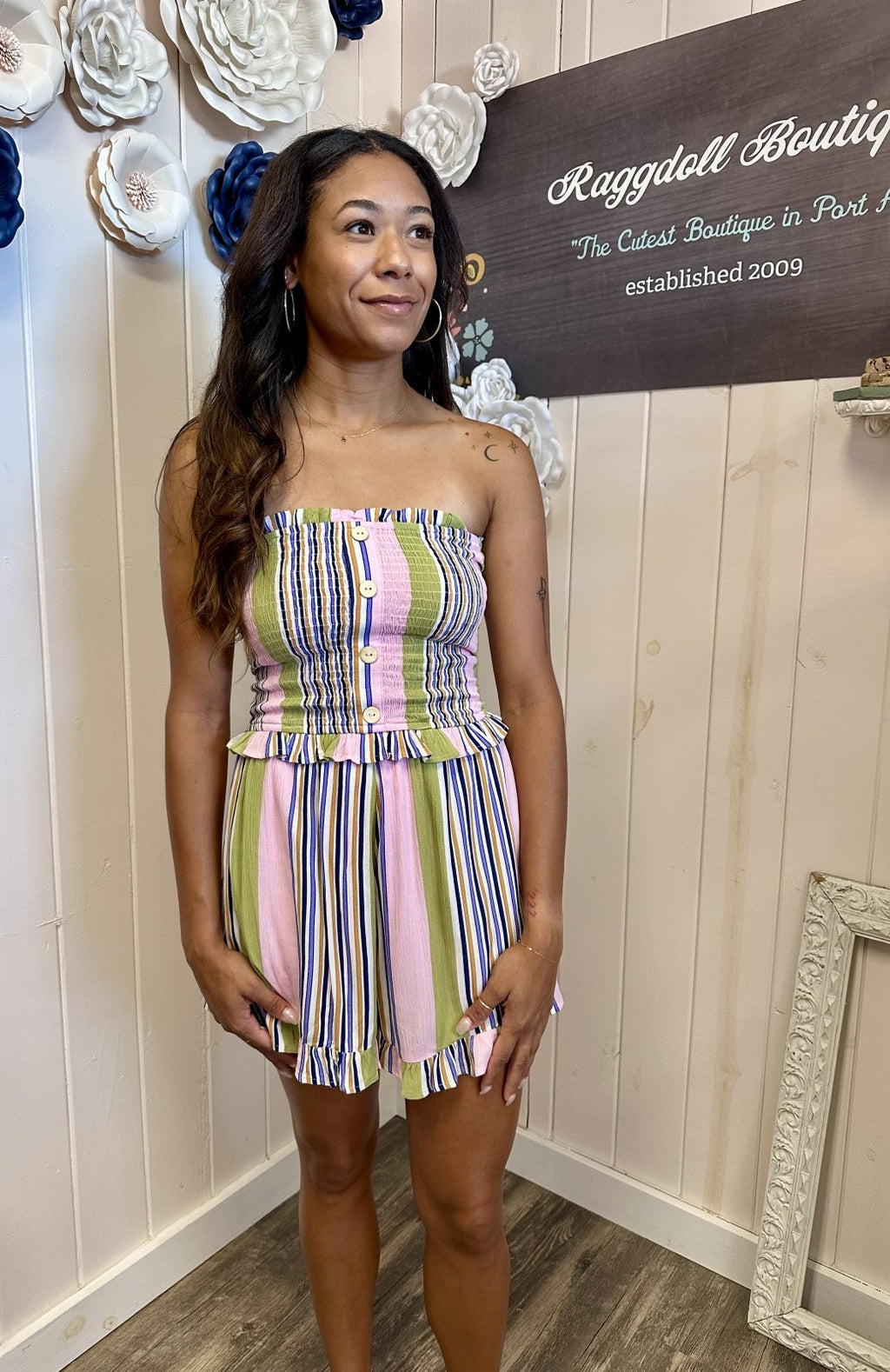 Lori romper featuring pink multi striped design, smocked bodice, and ruffled accents. Perfect for beach and tropical vacations.