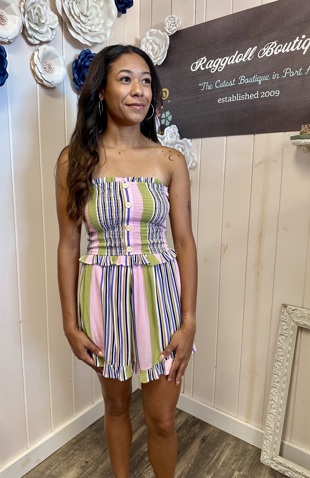 Lori romper featuring pink multi striped design, smocked bodice, and ruffled accents. Perfect for beach and tropical vacations.