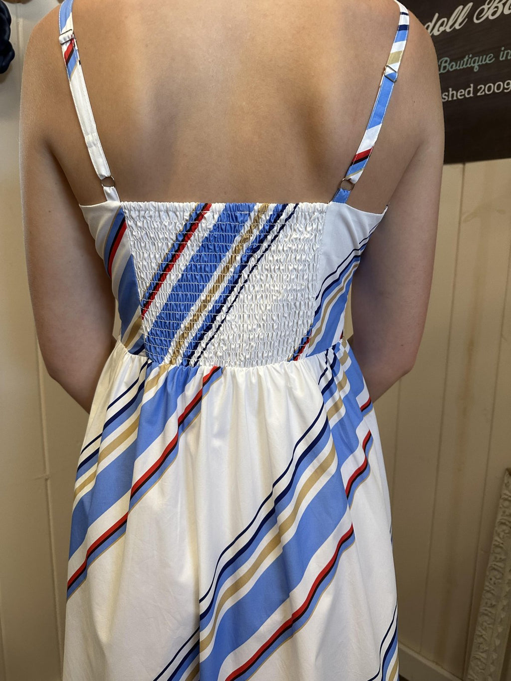 Back view of Fisher Dress showcasing smocked detail and colorful stripes from a coastal boutique clothing collection.