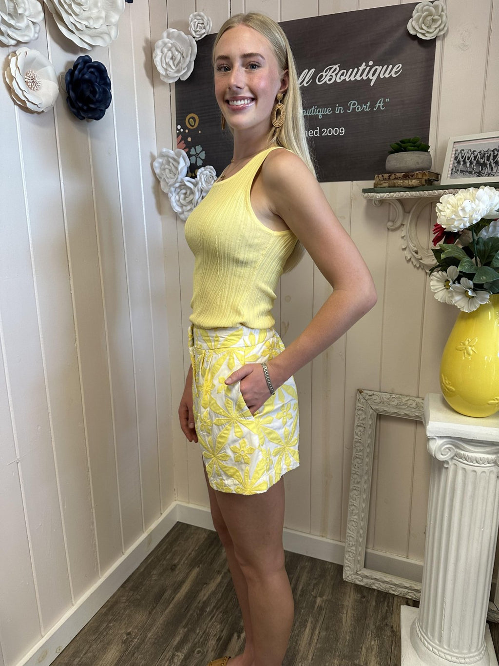 Stylish model in vibrant yellow Cami Shorts from a Port Aransas boutique, showcasing coastal women's fashion and boho vibes.