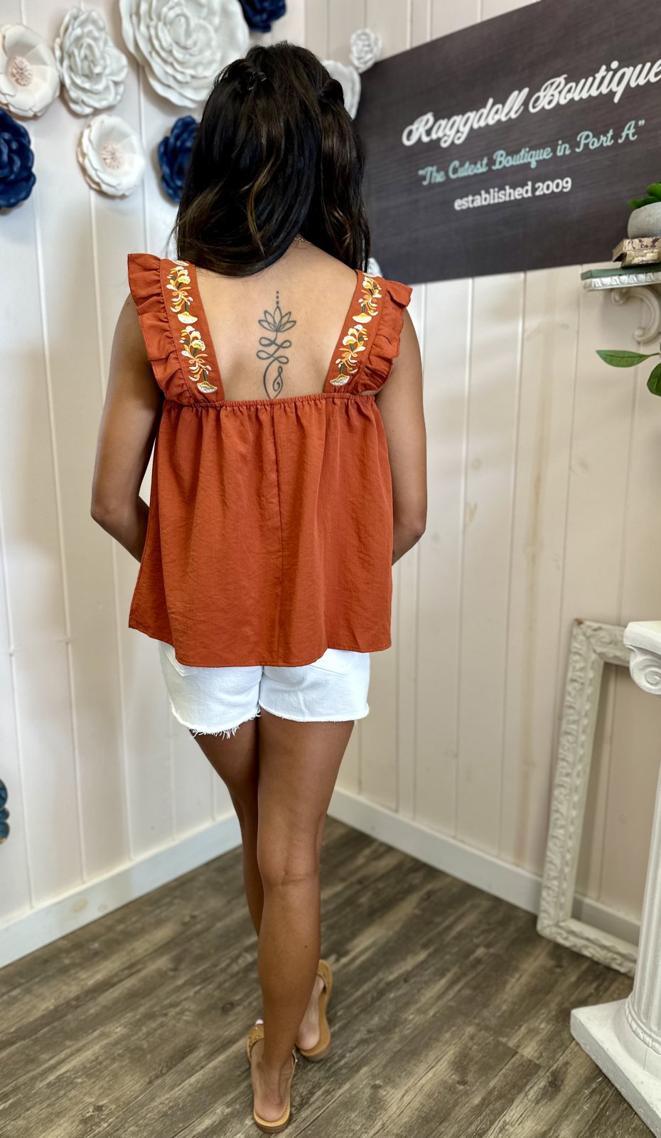 Back view of rust embroidered ruffle sleeve tank, a stylish top for women at a coastal boutique in Port Aransas.