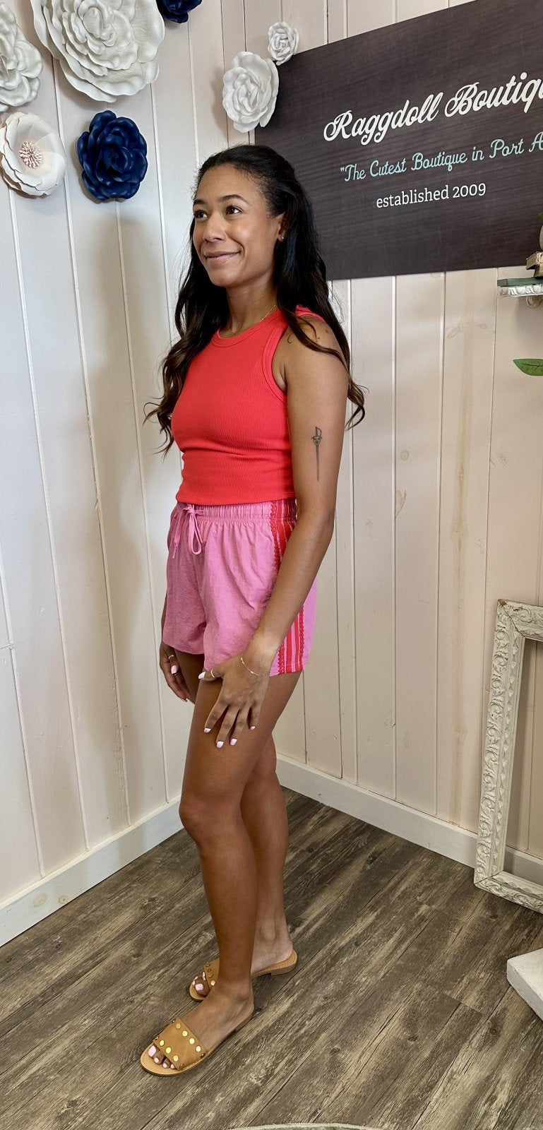 Stylish woman in pink side stripe and lace trim jersey shorts, perfect for coastal boutique clothing or casual outings.