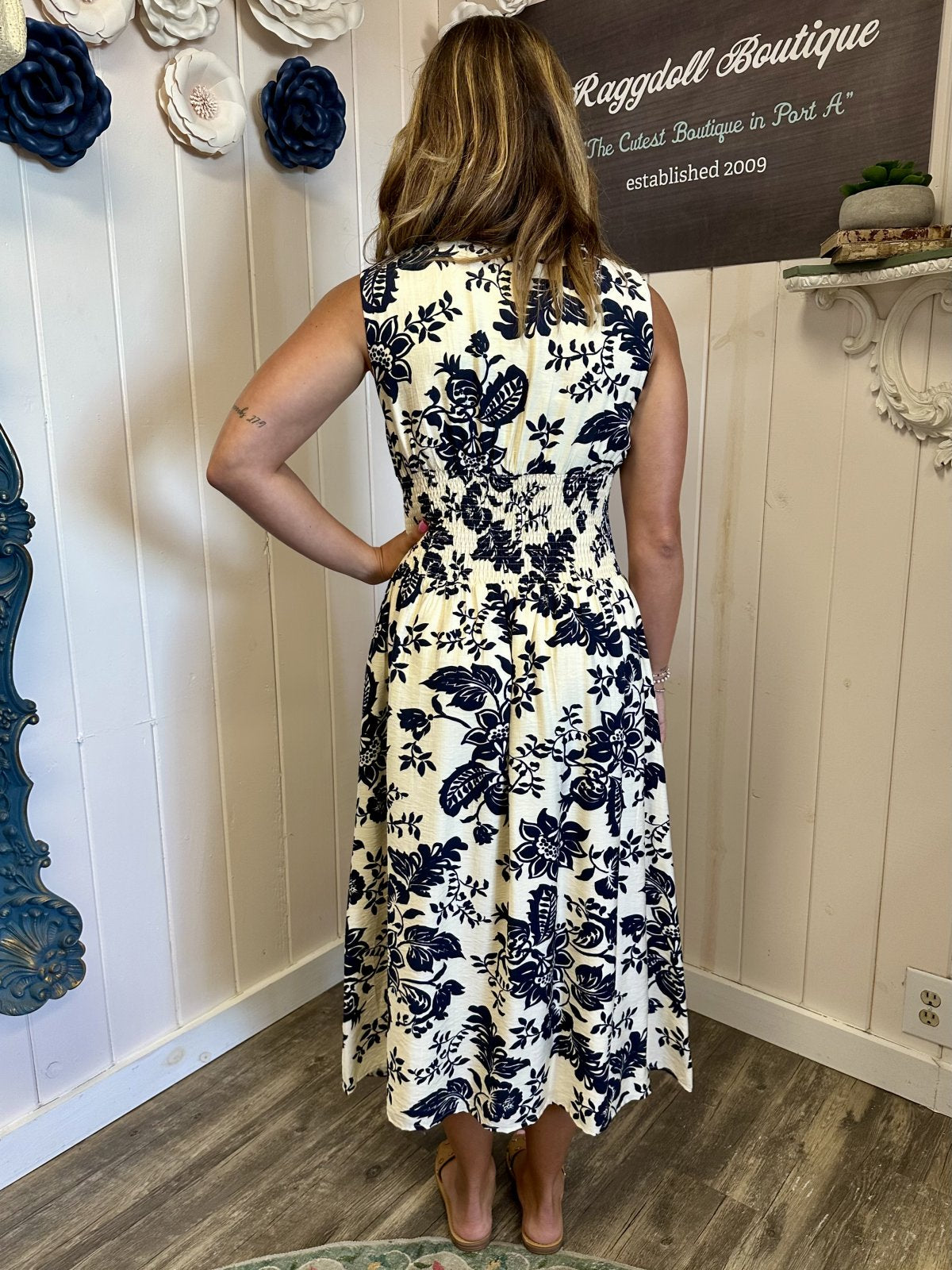 LeAnna Dress displayed at Raggdoll Boutique, showcasing a back view of the floral pattern in navy blue on a lightweight fabric.