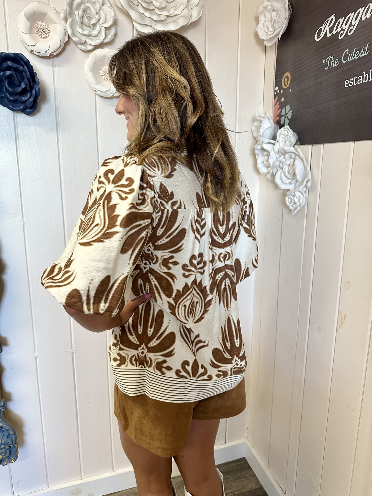 Back view of a woman wearing the Cammy Top from Raggdoll Boutique, showcasing camel color and bubble sleeves.