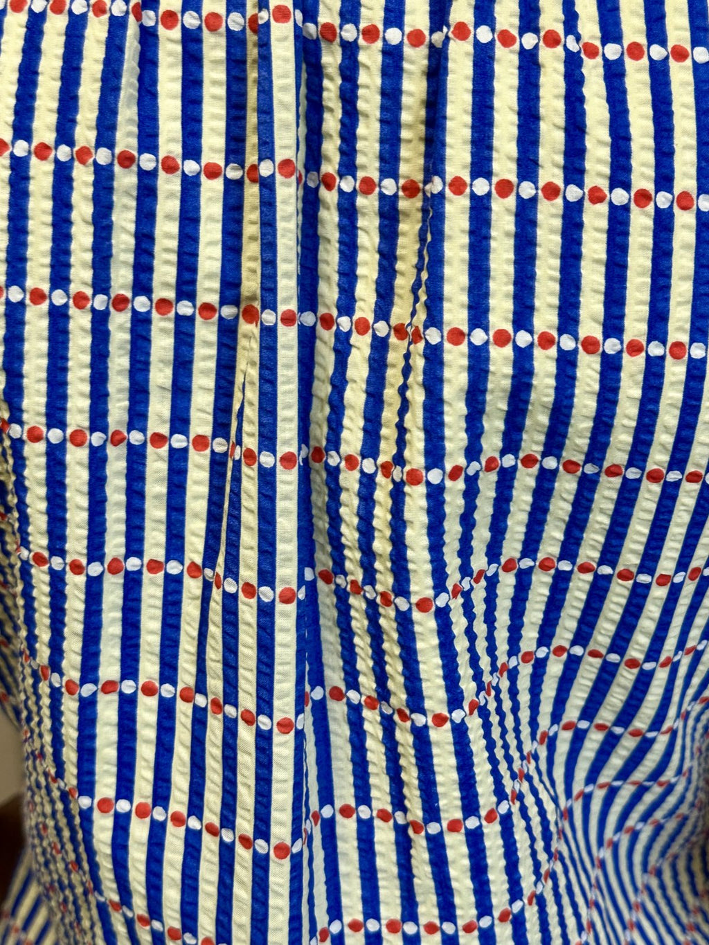Close-up of fabric with bold blue and cream stripes, perfect for coastal boutique clothing and tropical vacation dresses.