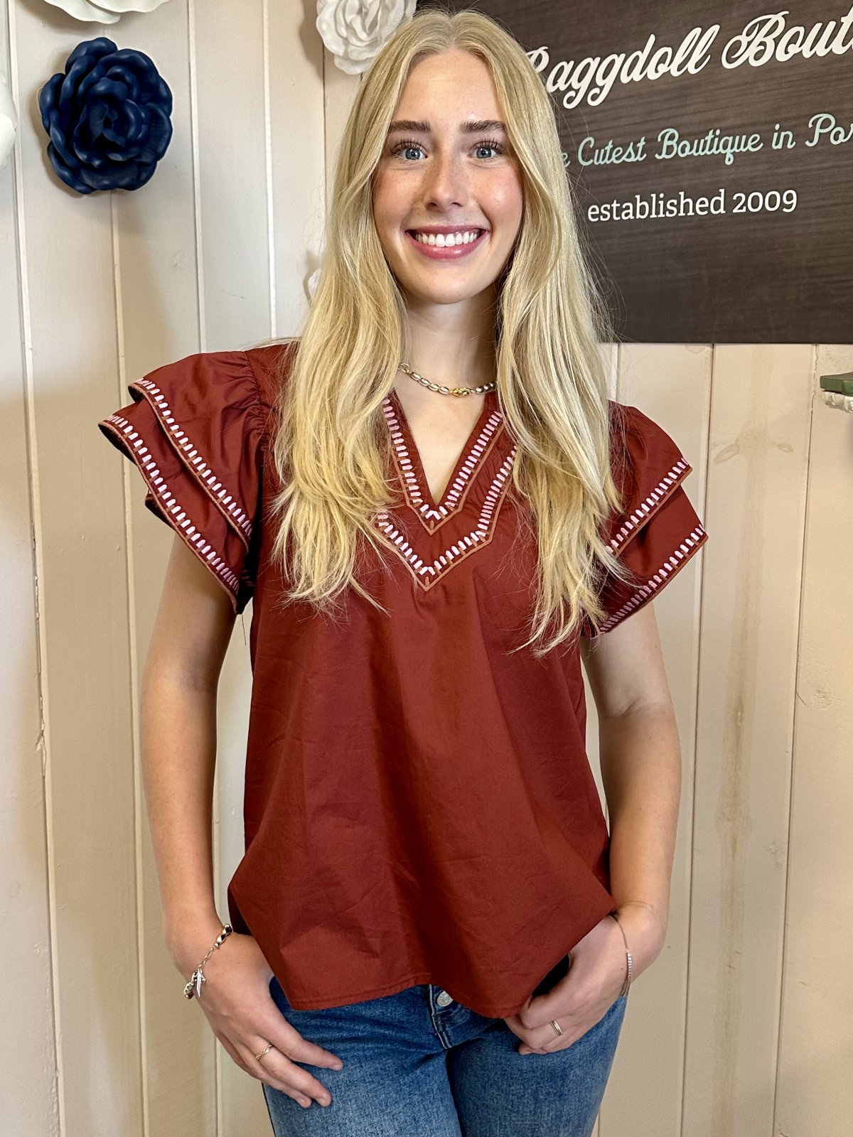 Model wearing the Willow Top from Raggdoll Boutique, showcasing ruffle flutter sleeves and embroidered trim V-neck.