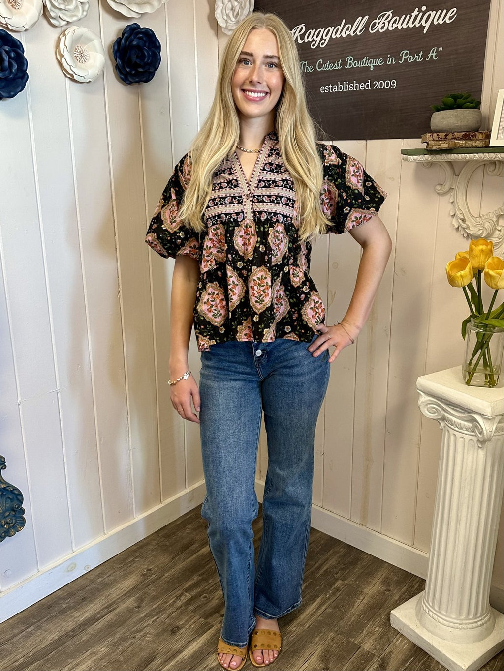 Sarah Top worn by model at Raggdoll Boutique showcasing black floral print with pink accents and puff sleeves.