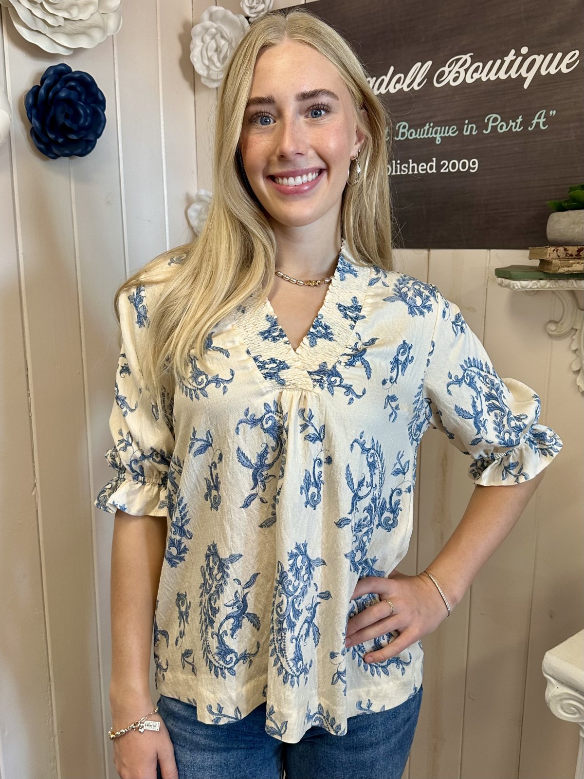 Woman wearing a trendy coastal blouse from Raggdoll Boutique, showcasing Port Aransas women's clothing styles.