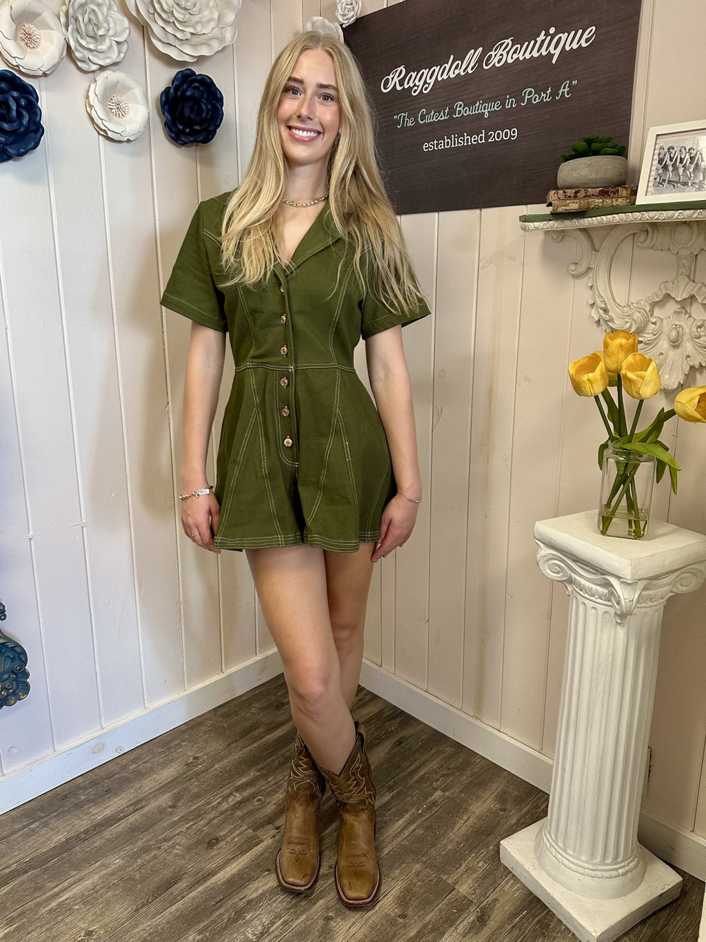 Model wearing Taylor Romper from Raggdoll Boutique, olive short sleeve romper with contrast stitching and button front.