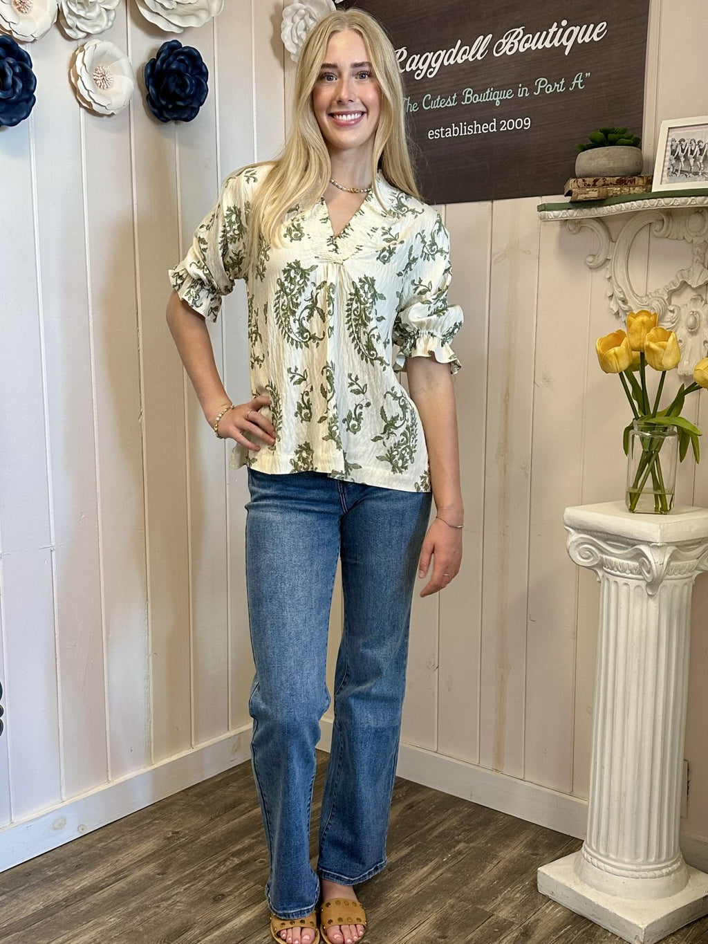 Woman wearing a floral top and jeans, showcasing trendy coastal style at Raggdoll Boutique, Port Aransas.