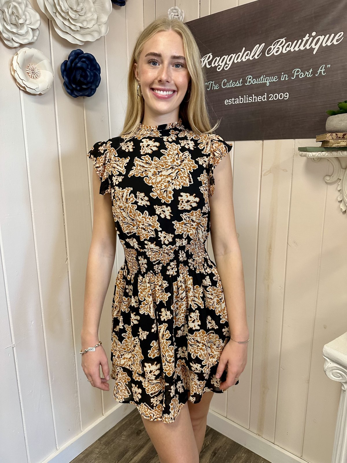Model wearing the Barrett Dress by Raggdoll Boutique, featuring a black print and smocked waist detail.
