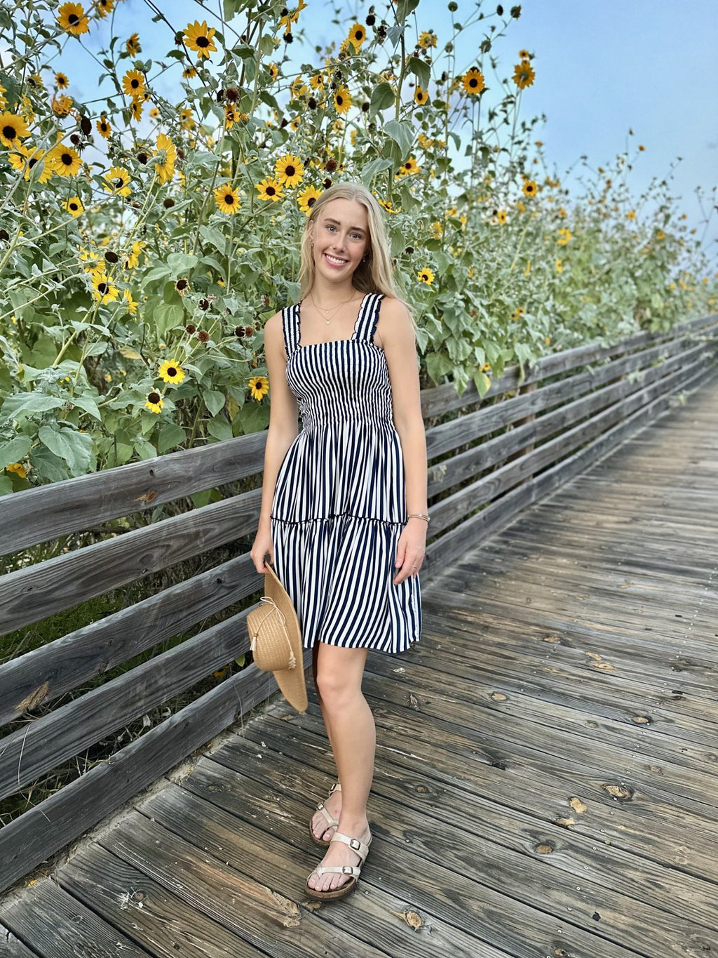 Woman in a lacy dress with navy and white stripes at a coastal setting, embodying trendy coastal style from Raggdoll Boutique.