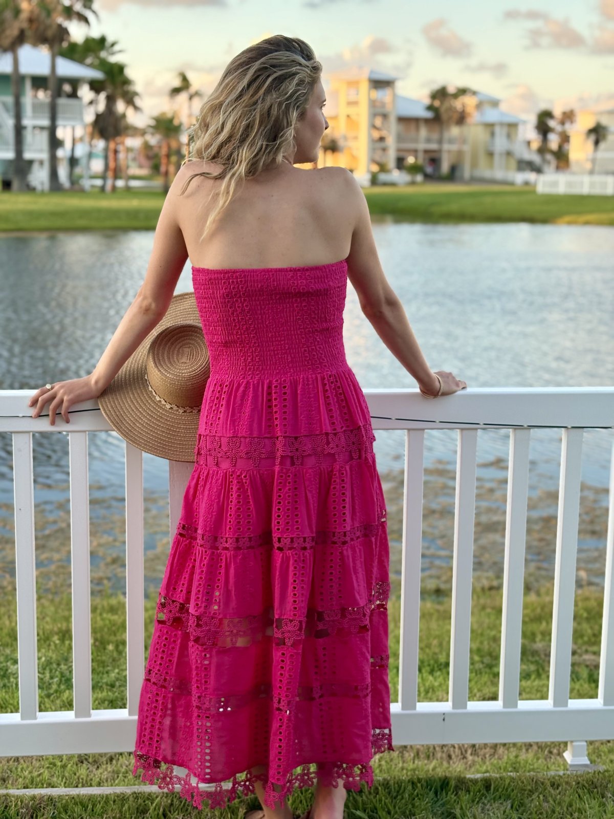 Model wearing Nixie Dress in Fuchsia by Raggdoll Boutique, showcasing trendy coastal style near water.