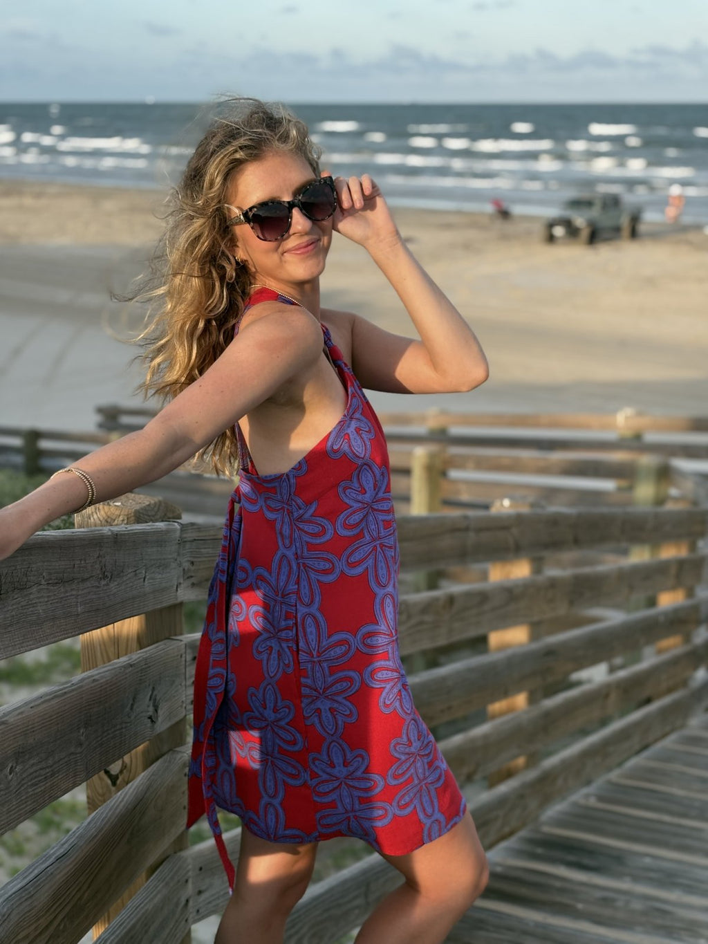 Stylish woman in Cherry Blue halter mini dress by the beach, perfect for tropical vacations and curated women's fashion.
