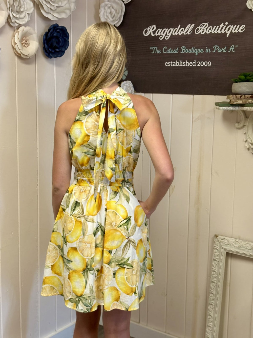 Back view of a white lemon print mini dress from a coastal boutique, perfect for summer beachwear.