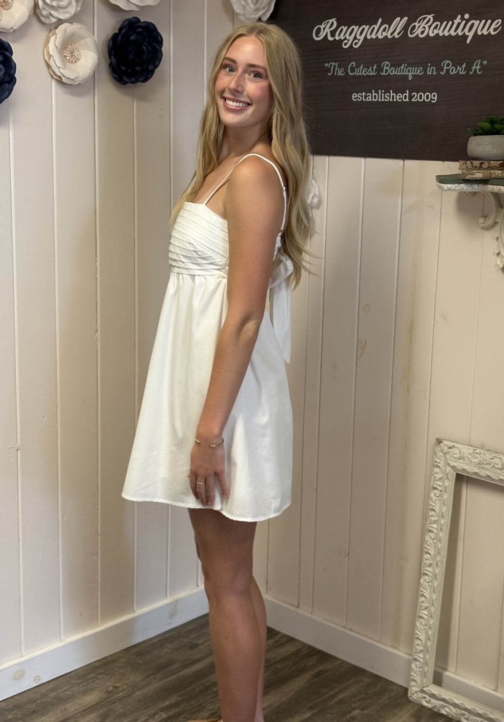 Off-white pleated dress with chic cut-out back, perfect for beach outings. Available at Raggdoll Boutique in Port Aransas.