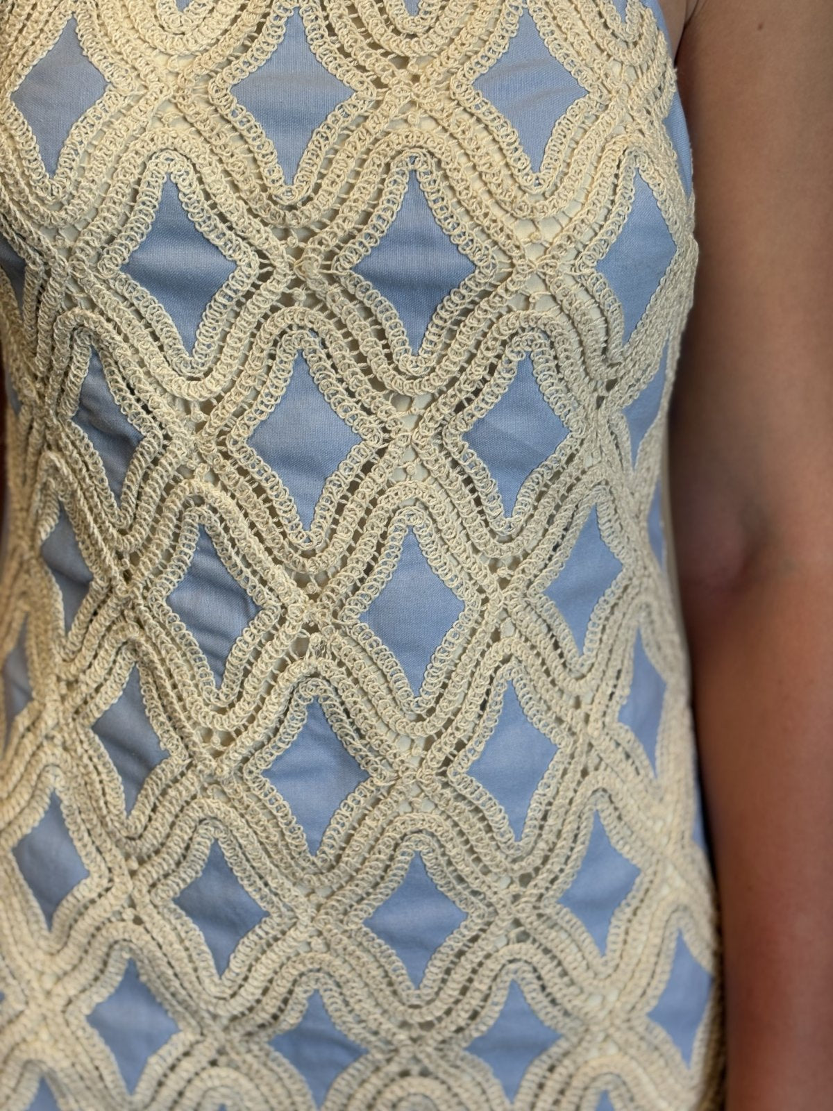 Close-up of a stylish sleeveless mini dress with crochet lace and chambray fabric, perfect for coastal boutique clothing.