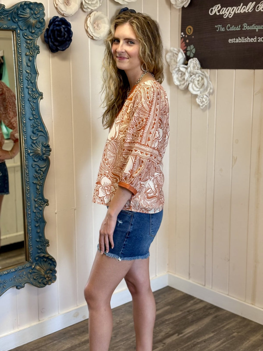 Orange and white top with 3/4 sleeves presented in a coastal boutique, perfect for stylish game day outfits.