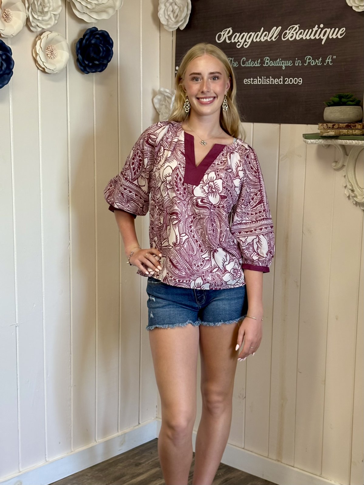 Model in stylish floral blouse from Raggdoll Boutique, showcasing curated women's fashion in Port Aransas, ideal for beach outings.