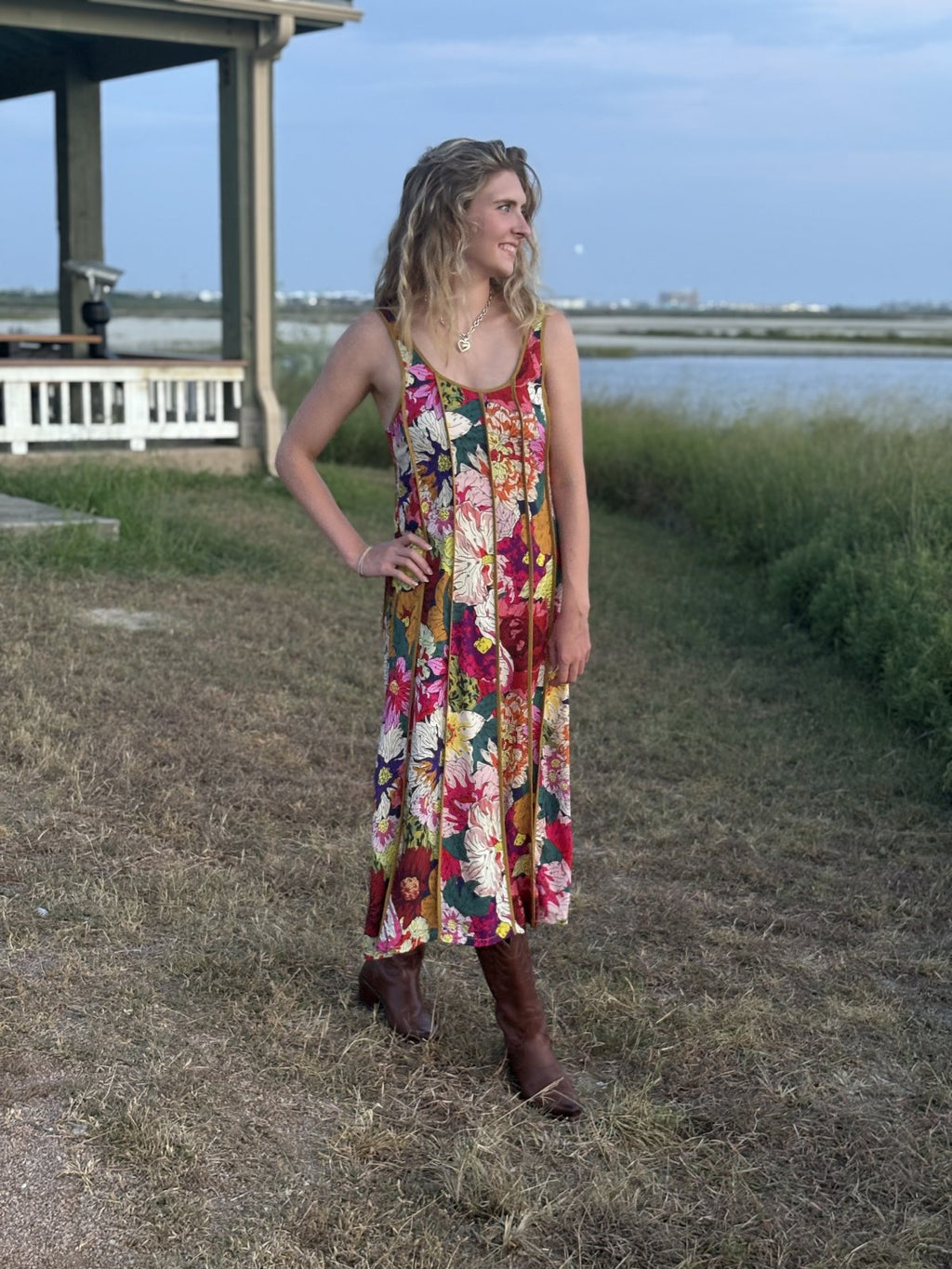 Model wearing a floral midi dress outdoors, showcasing coastal boutique clothing, perfect for beach outings or festivals.