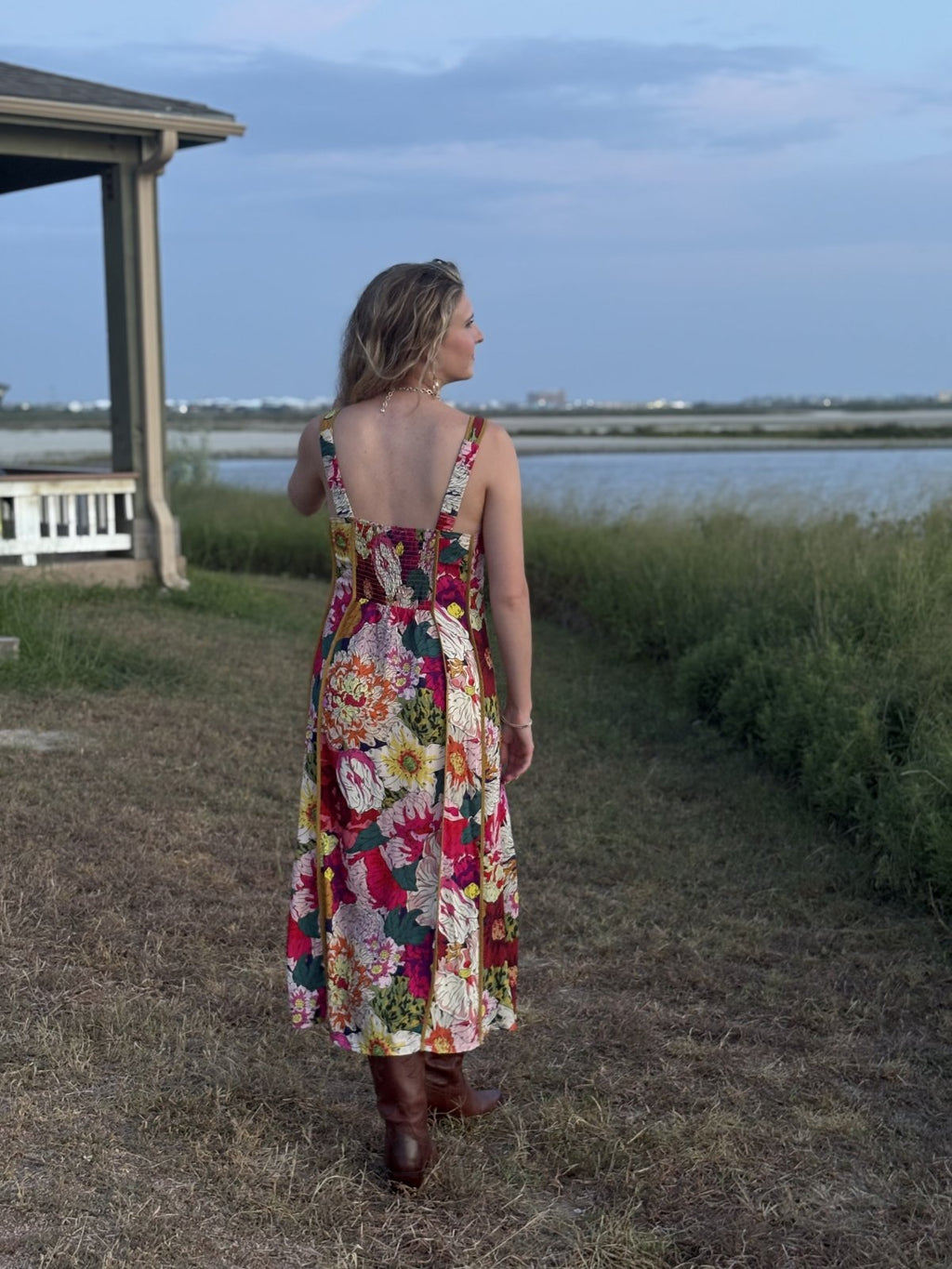 Woman wearing a floral midi dress, perfect for coastal boutique clothing and beach dresses, ideal for sunny days.