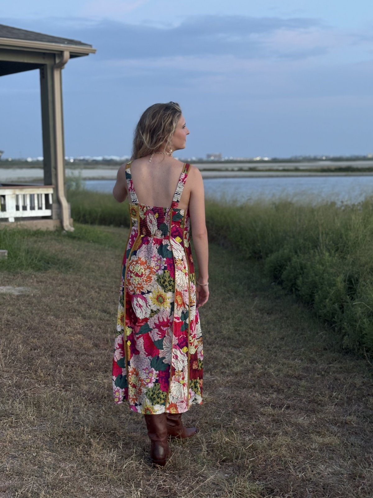 Woman wearing a floral midi dress, perfect for coastal boutique clothing and beach dresses, ideal for sunny days.