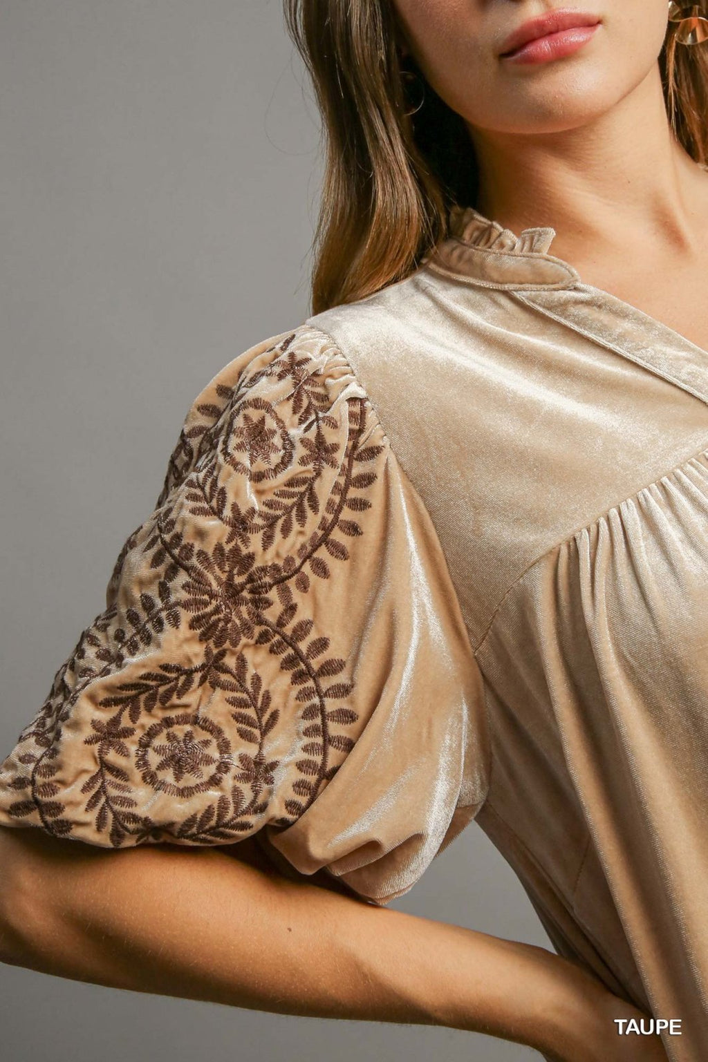 Close-up of a woman in a taupe dress with embroidered sleeves, ideal for coastal boutique clothing and beach dresses.