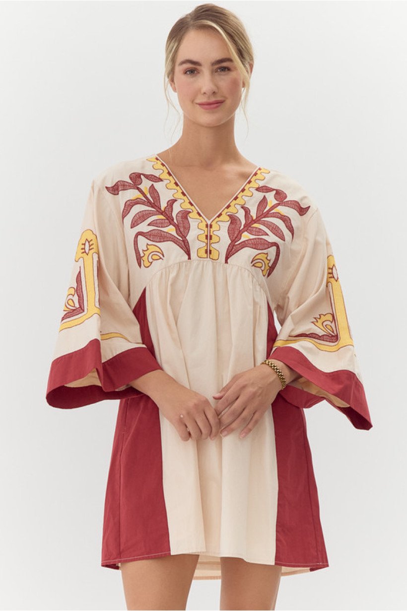 Talia Dress at a coastal boutique, featuring 100% cotton, vibrant embroidery, perfect for beach days and tropical vacations.