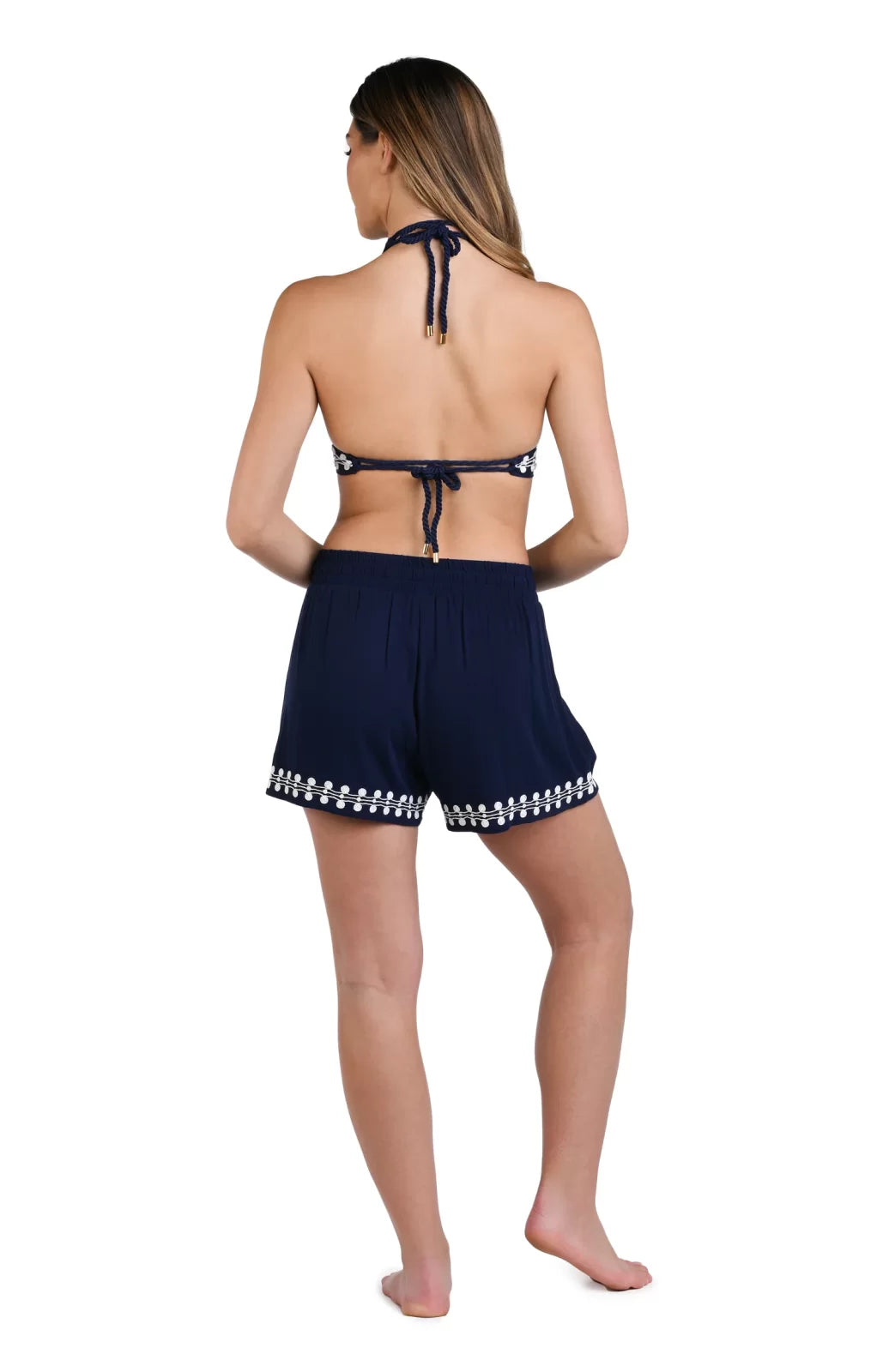 Back view of a woman wearing Sea Scallops Navy/White Beach Shorts and a matching bikini top from Raggdoll Boutique.