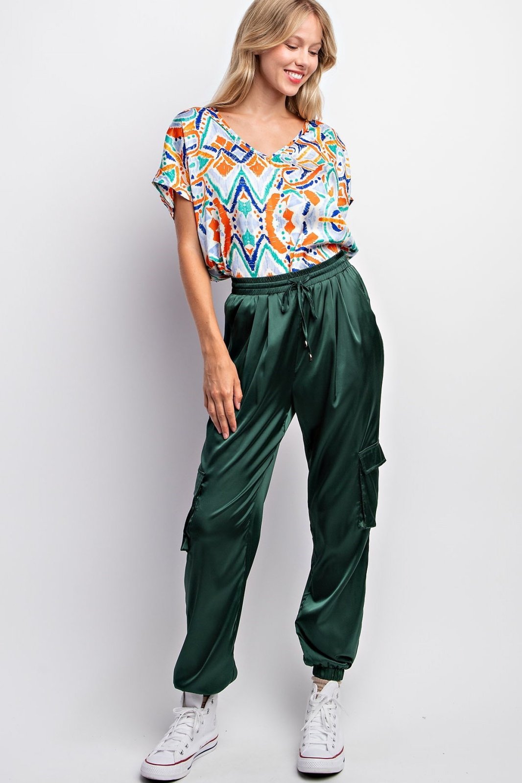 Women in colorful top wearing AMAZON GREEN SATIN JOGGERS from Raggdoll Boutique, perfect for trendy coastal style.