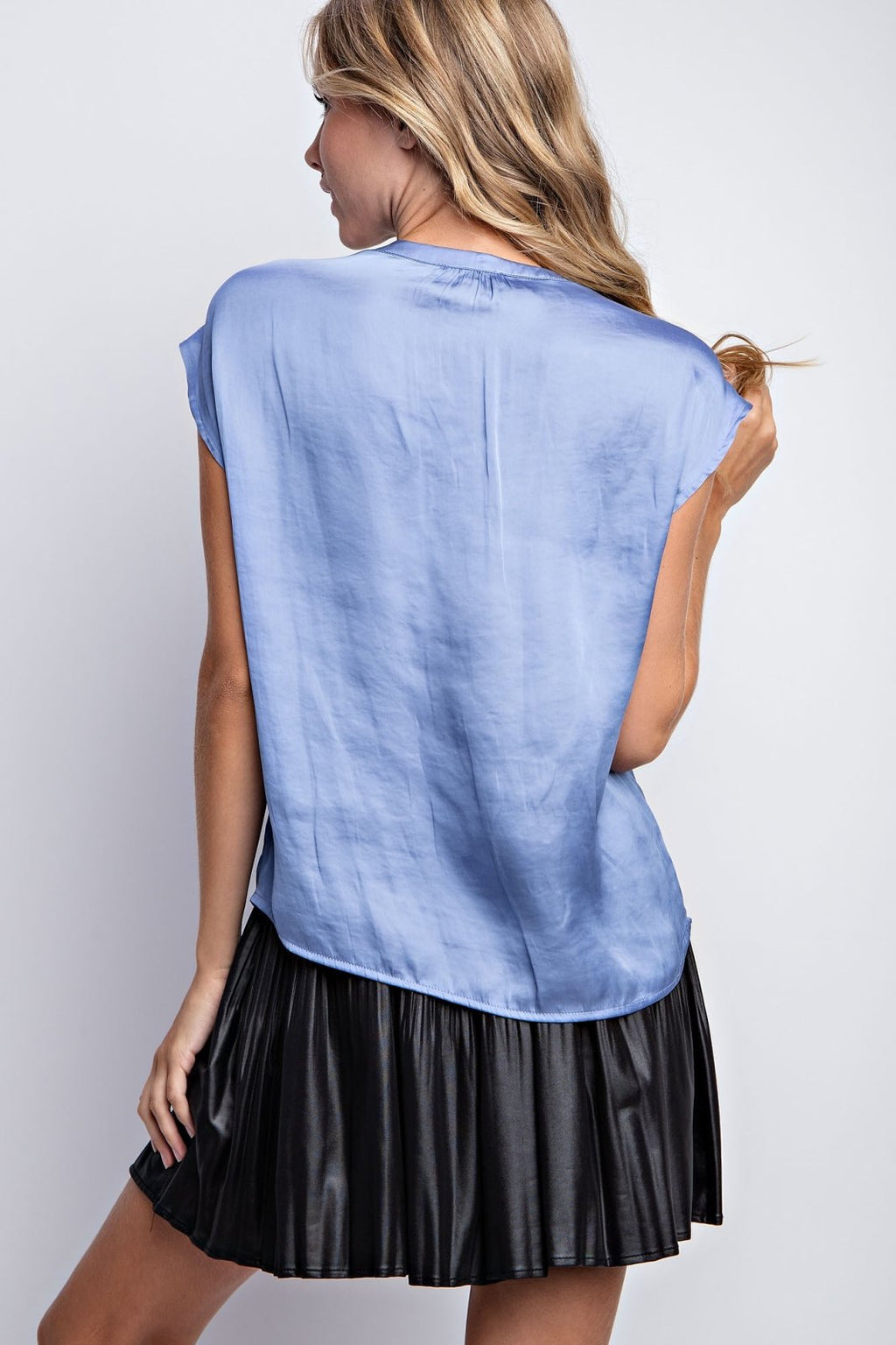 Back view of a model wearing a CORN FLOWER BLUE TOP paired with a black skirt, showcasing trendy coastal style.